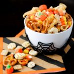 spooky snack mix in a spider bowl with a striped Halloween napkin