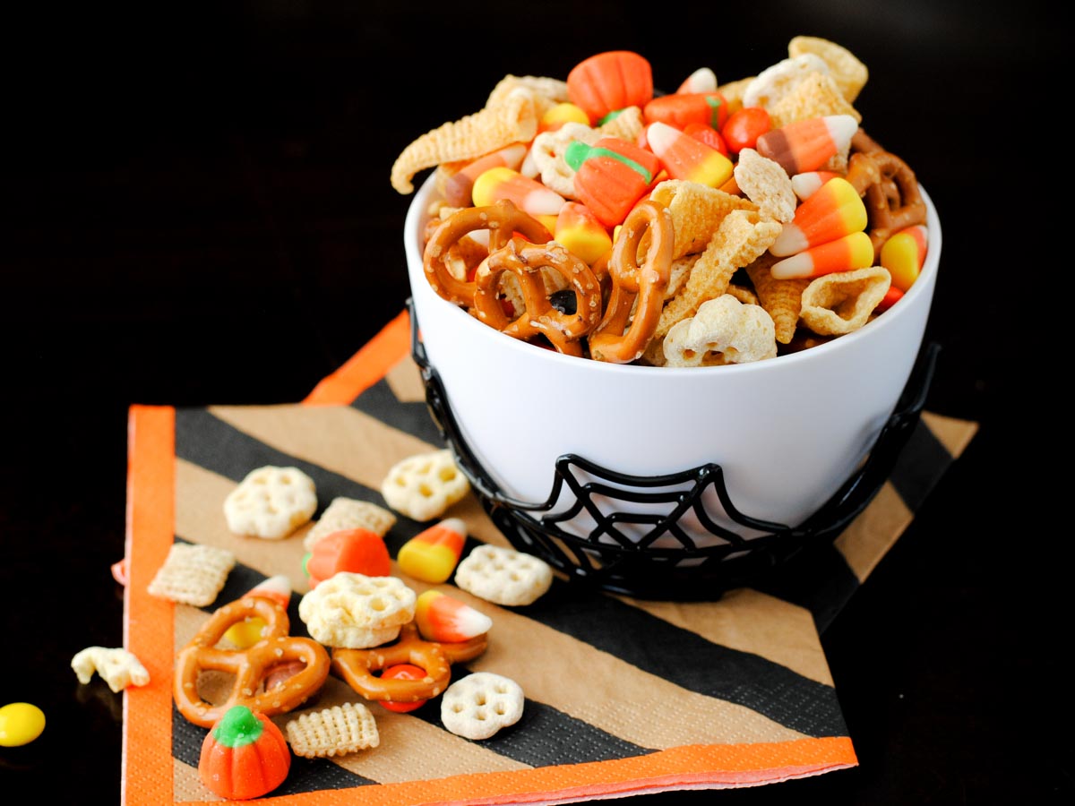 spooky snack mix in a spider bowl with a striped Halloween napkin