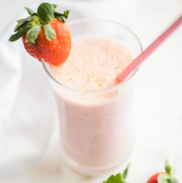 strawberry cheese cake smoothie garnished with strawberry and a pink straw