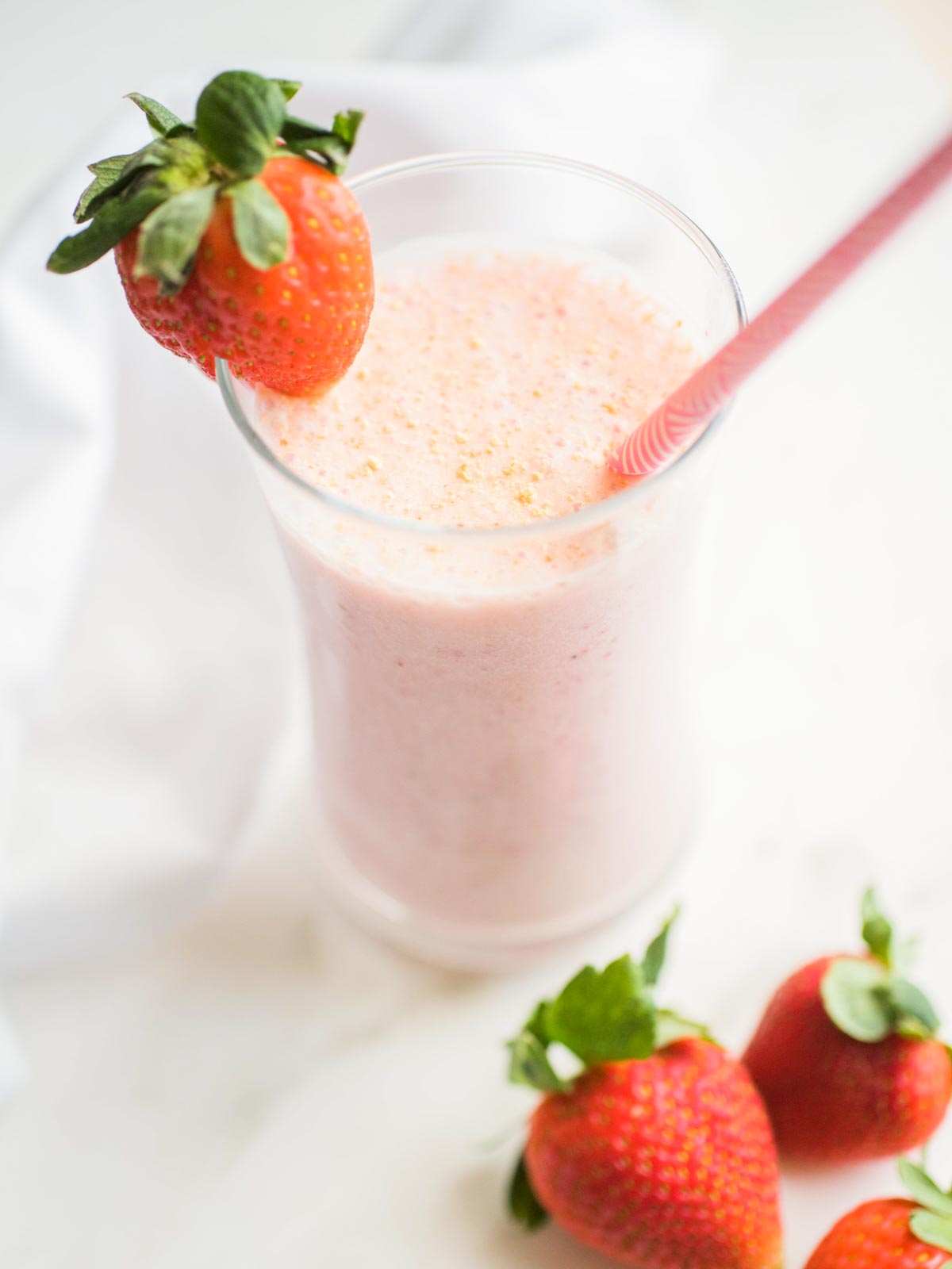 glass of strawberry cheesecake smoothie garnished with a strawberry