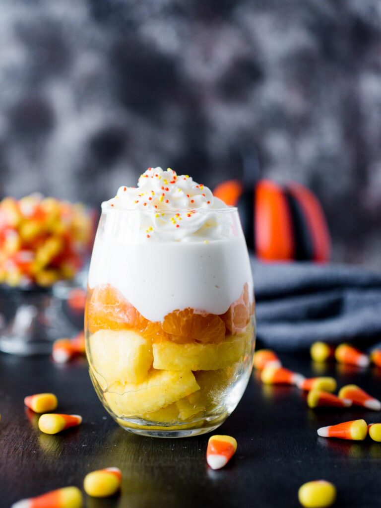 fruit parfait in glass surrounded by candy corn