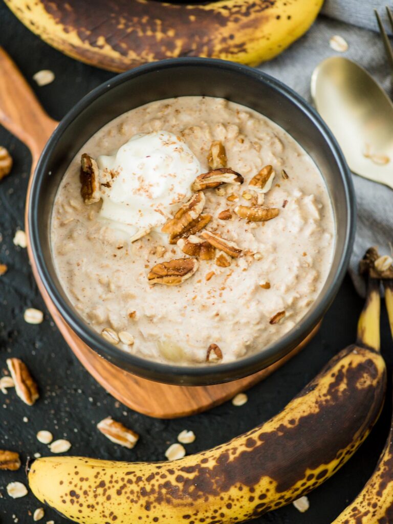 banana bread overnight oats in a bowl topped with pecans and whipped cream