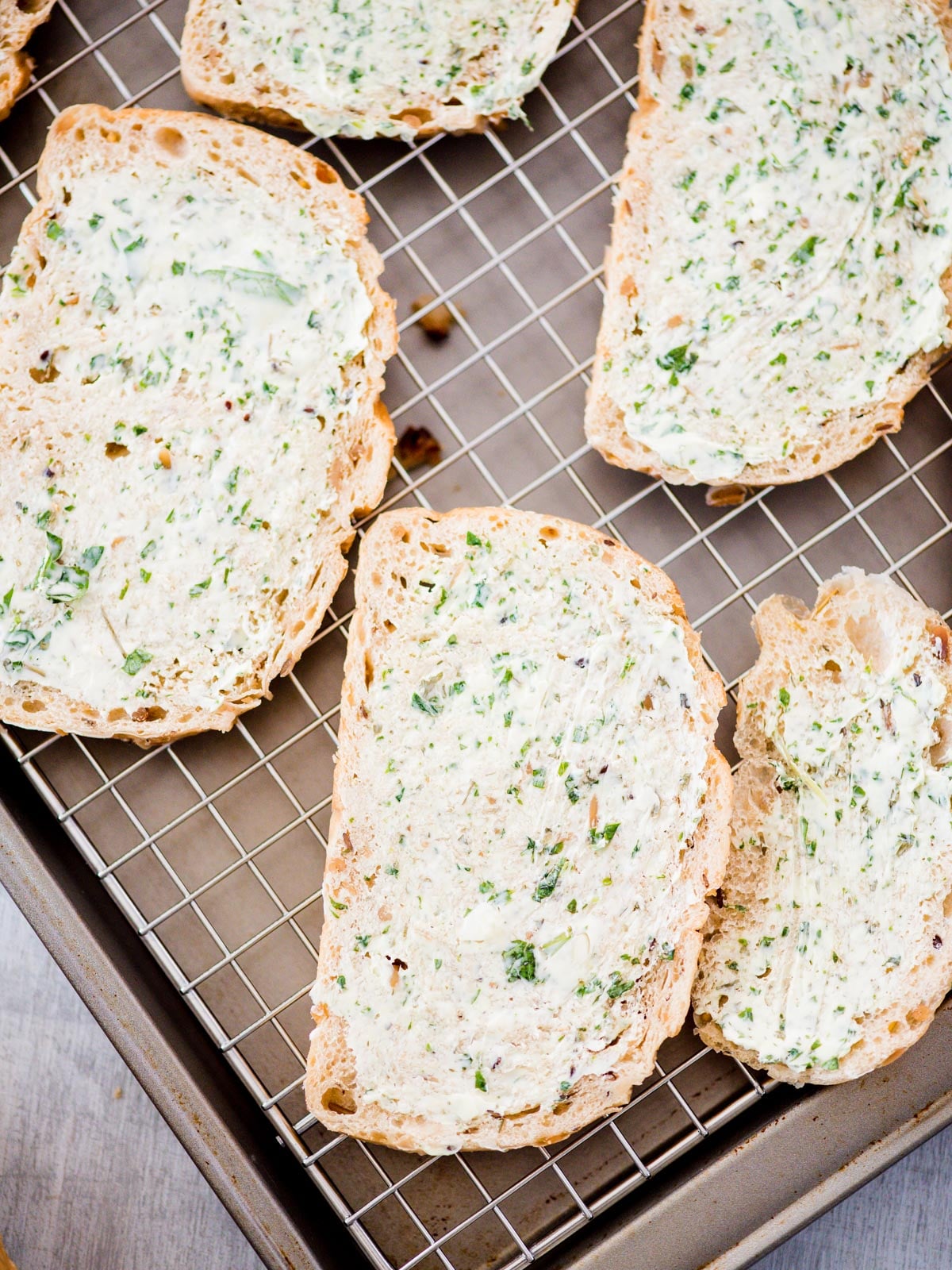 butter mixture spread on bread slices on pan