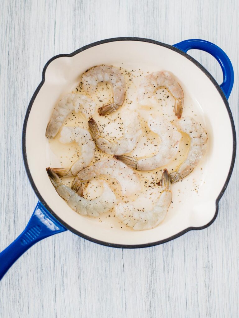 raw shrimp in skillet with salt and pepper