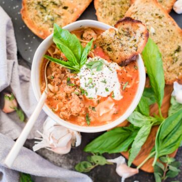 one-pot lasagna soup topped with ricotta basil and garlic bread