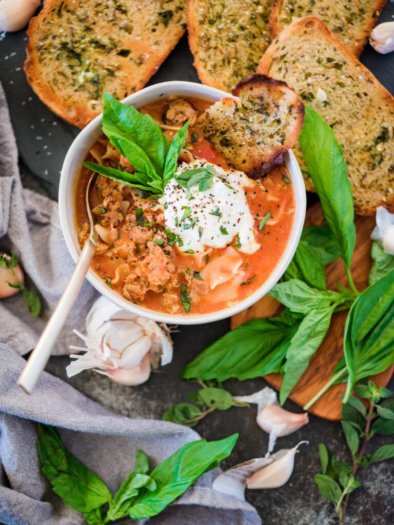 lasagna soup with garlic bread and topped with ricotta and basil