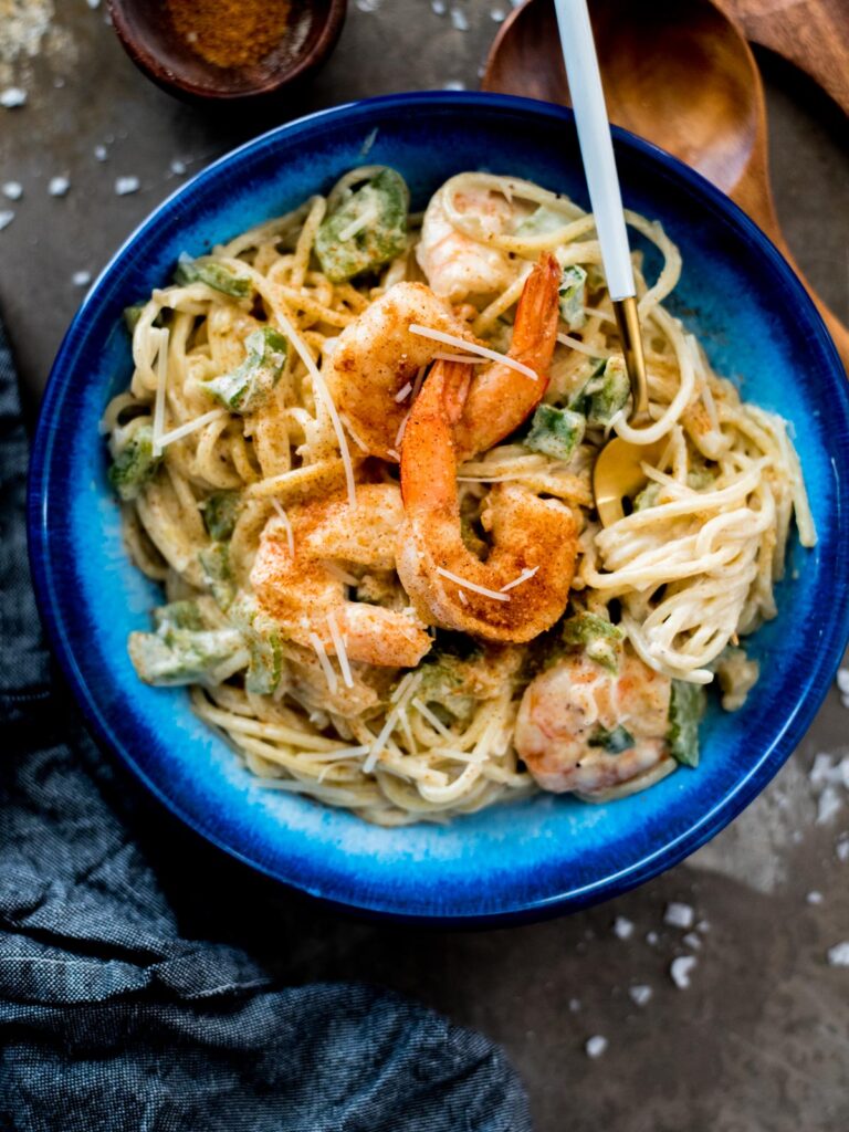 cajun shrimp alfredo in a blue bowl topped with parmesan