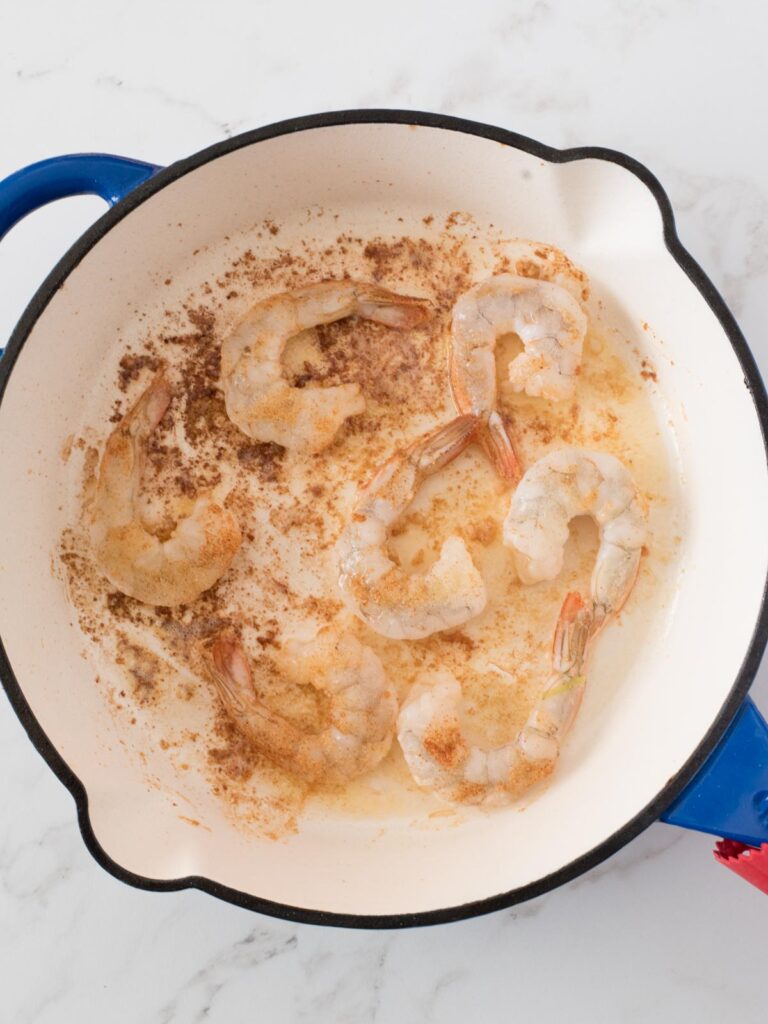 shrimp cooking in a skillet with cajun spices