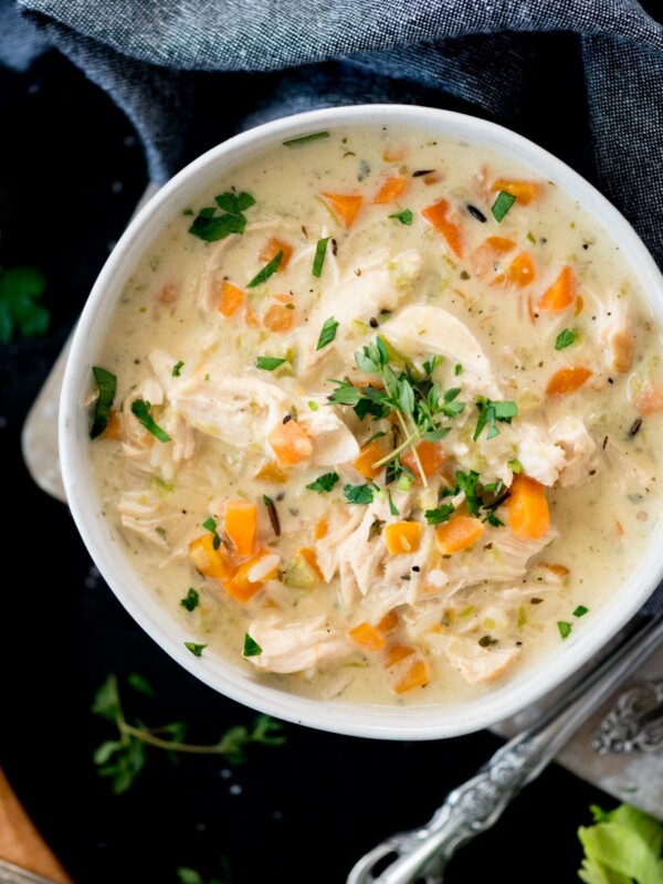 Creamy chicken and rice soup in a bowl topped with parsley and thyme