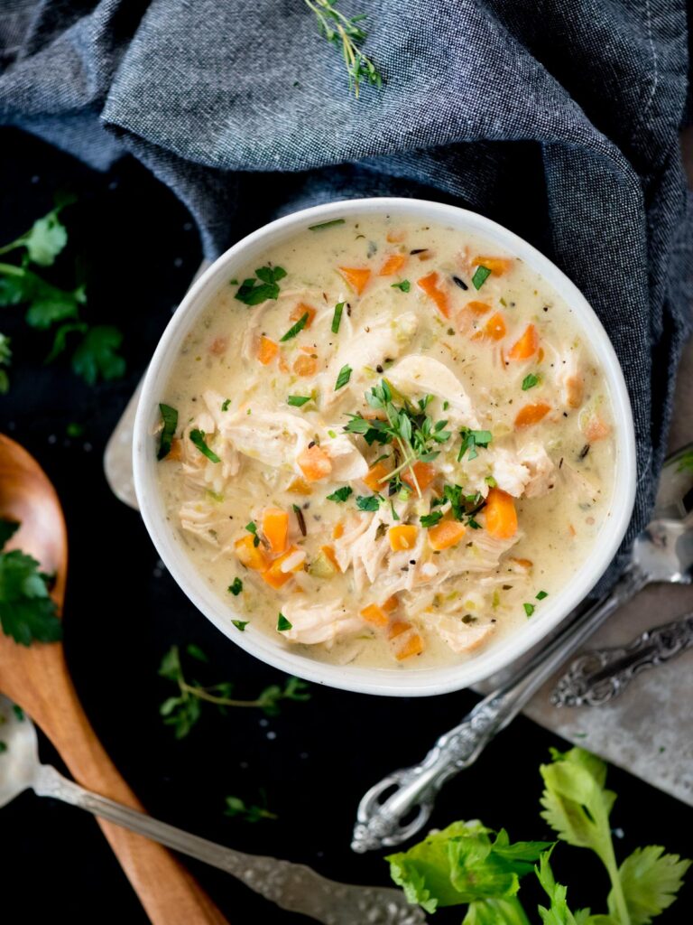 Creamy chicken and rice soup in a bowl topped with parsley and thyme