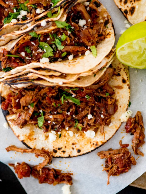 mexican shredded beef inside tacos topped with cilantro and queso fresco