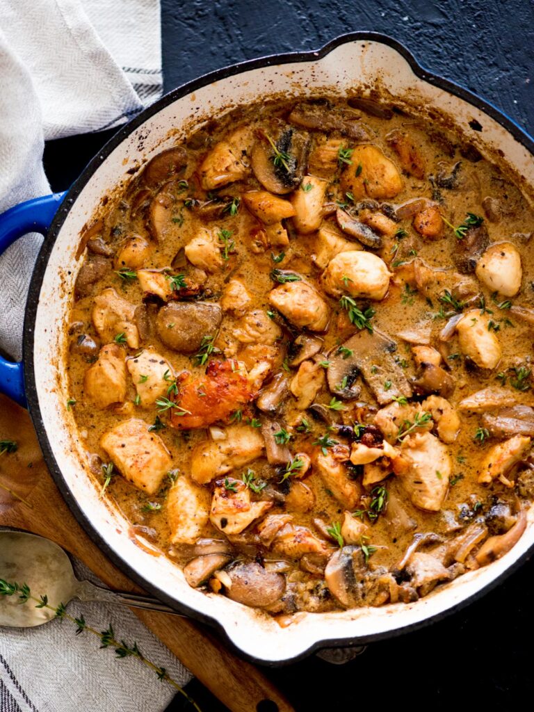 chicken and mushroom stroganoff in a skillet topped with fresh thyme