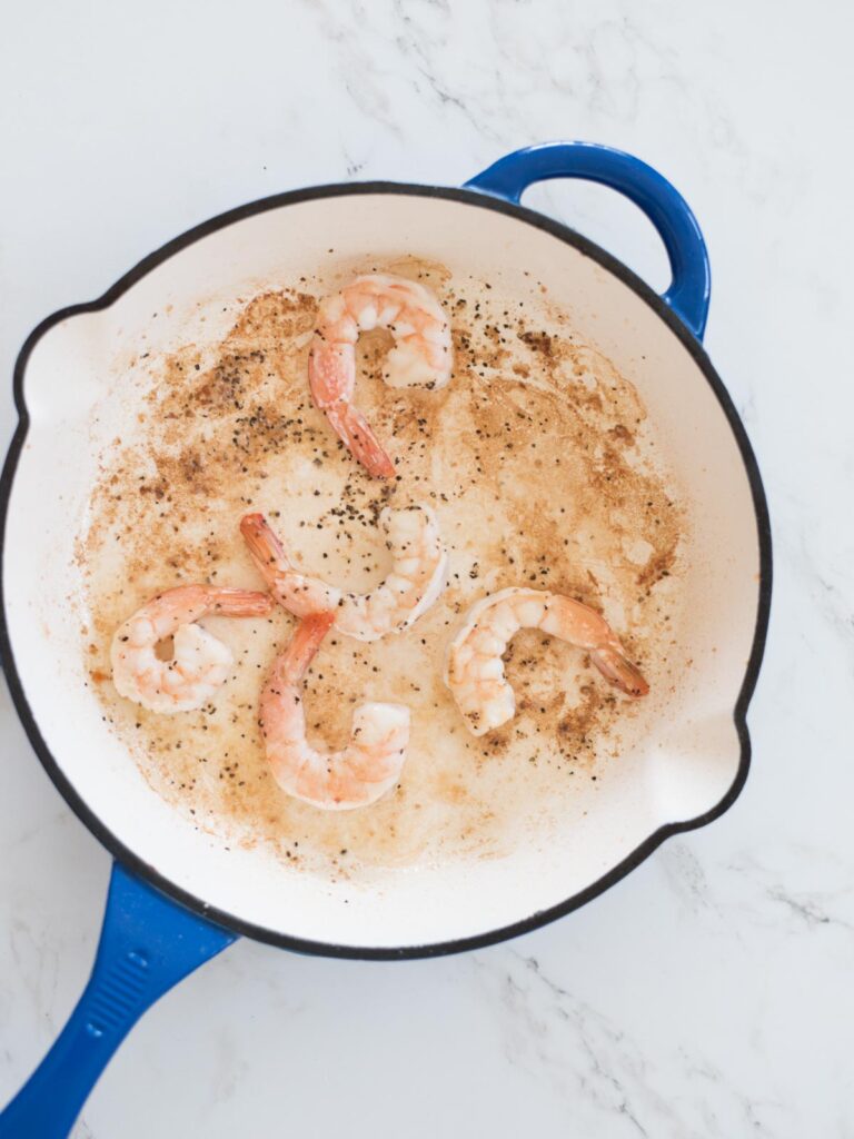 shrimp being cooked in an enamel cast iron skillet