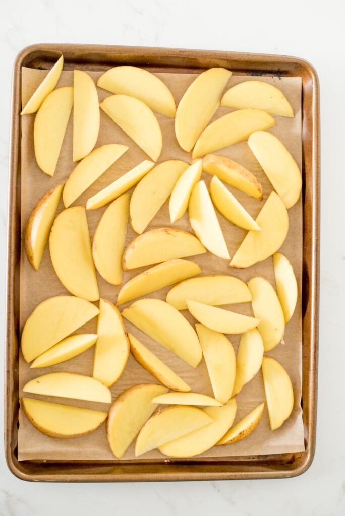 cut potato wedges on a parchment lined baking sheet