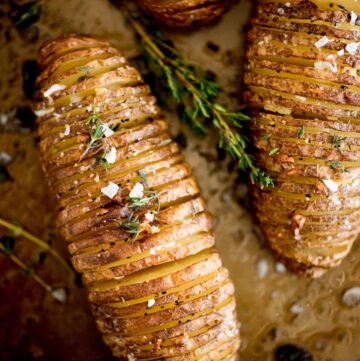 garlic butter hasselback potatoes topped with fresh thyme and flaked salt