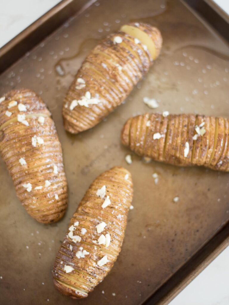 garlic butter placed on hasselback potatoes