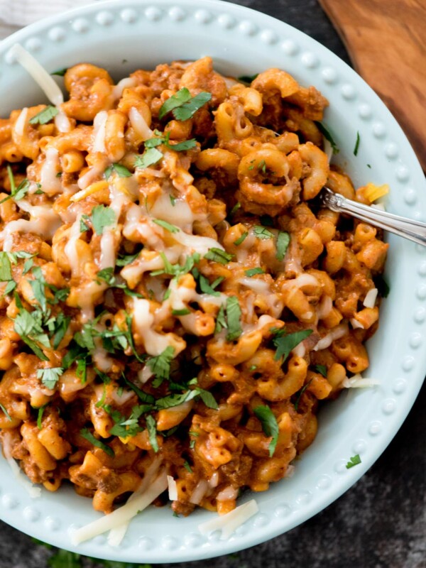 one pot cheesy taco pasta in a blue bowl topped with cheese and cilantro