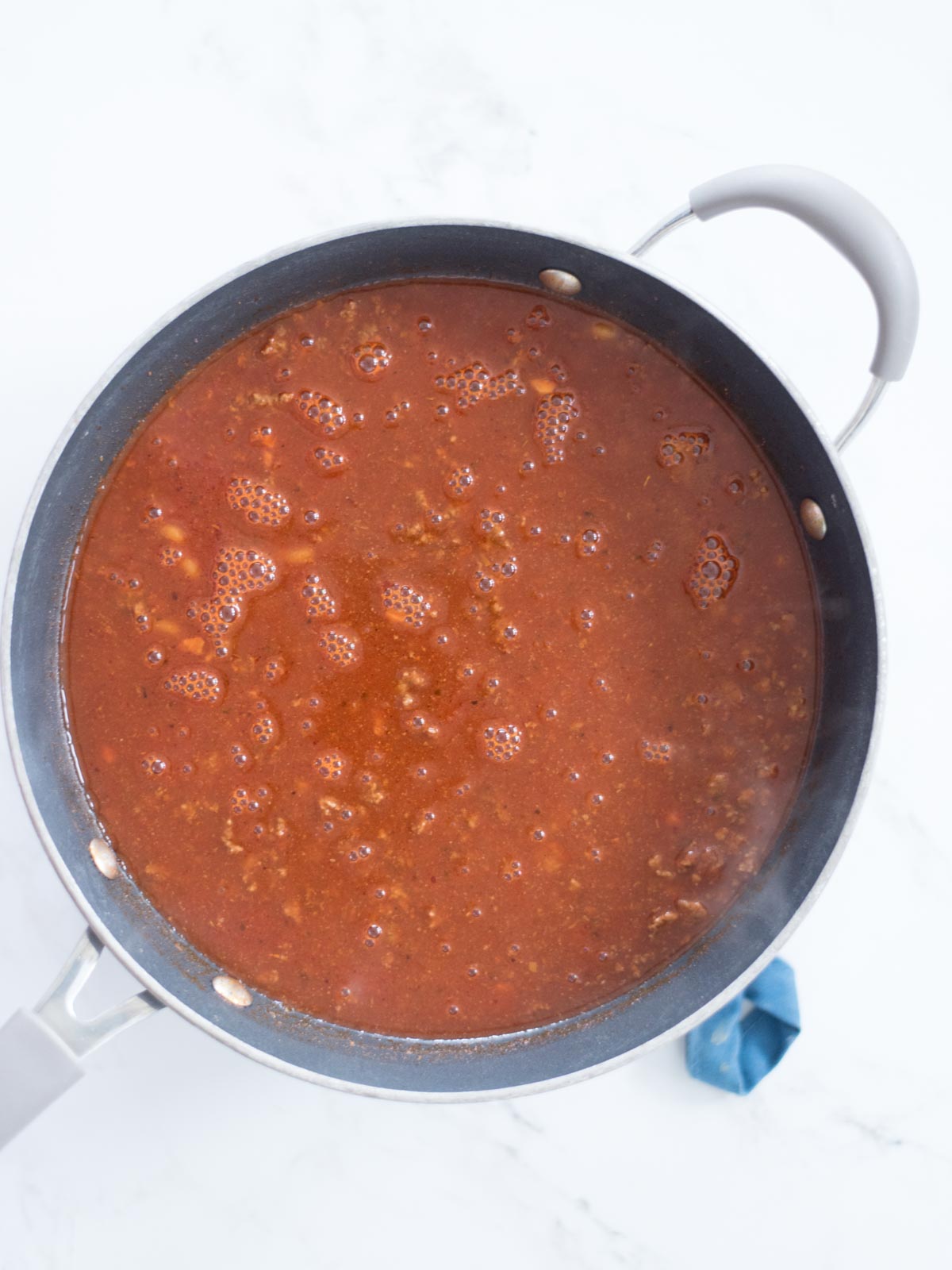 enchilada sauce, beef broth, and tomato sauce added to skillet with ground beef