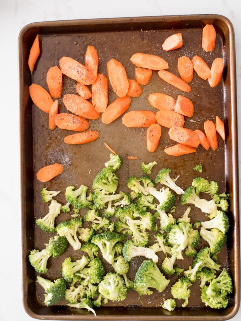 partially roasted broccoli and carrots on a sheet pan