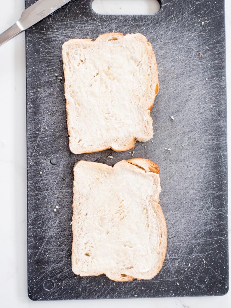 two buttered slices of bread on a cutting board