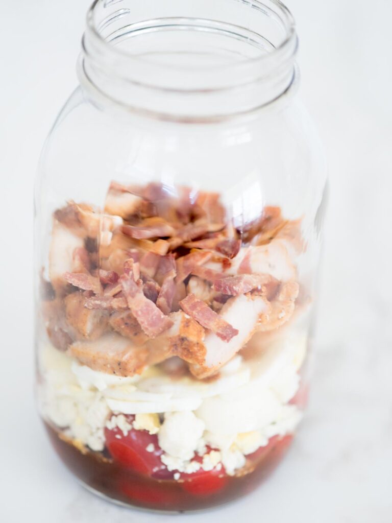 balsamic vinaigrette, tomatoes, gorgonzola, chives, egg, chicken, and bacon in a mason jar