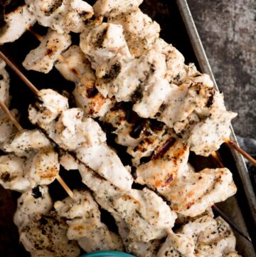greek grilled chicken skewers stacked together with tzatziki sauce