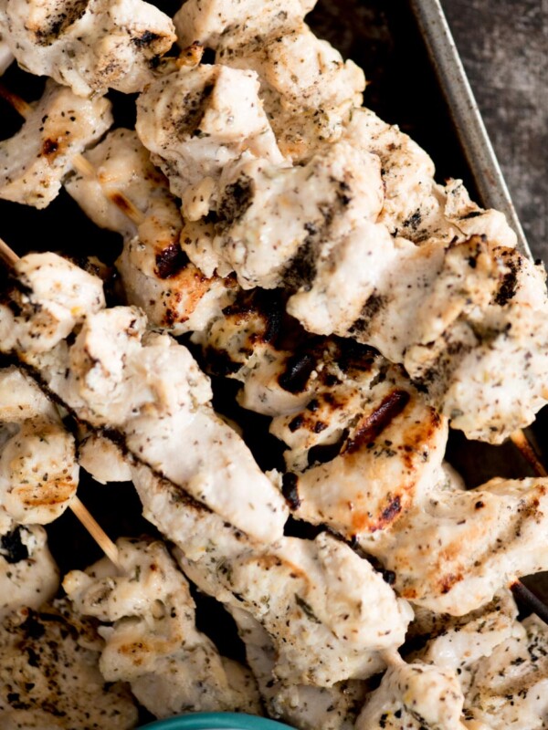 greek grilled chicken skewers stacked together with tzatziki sauce