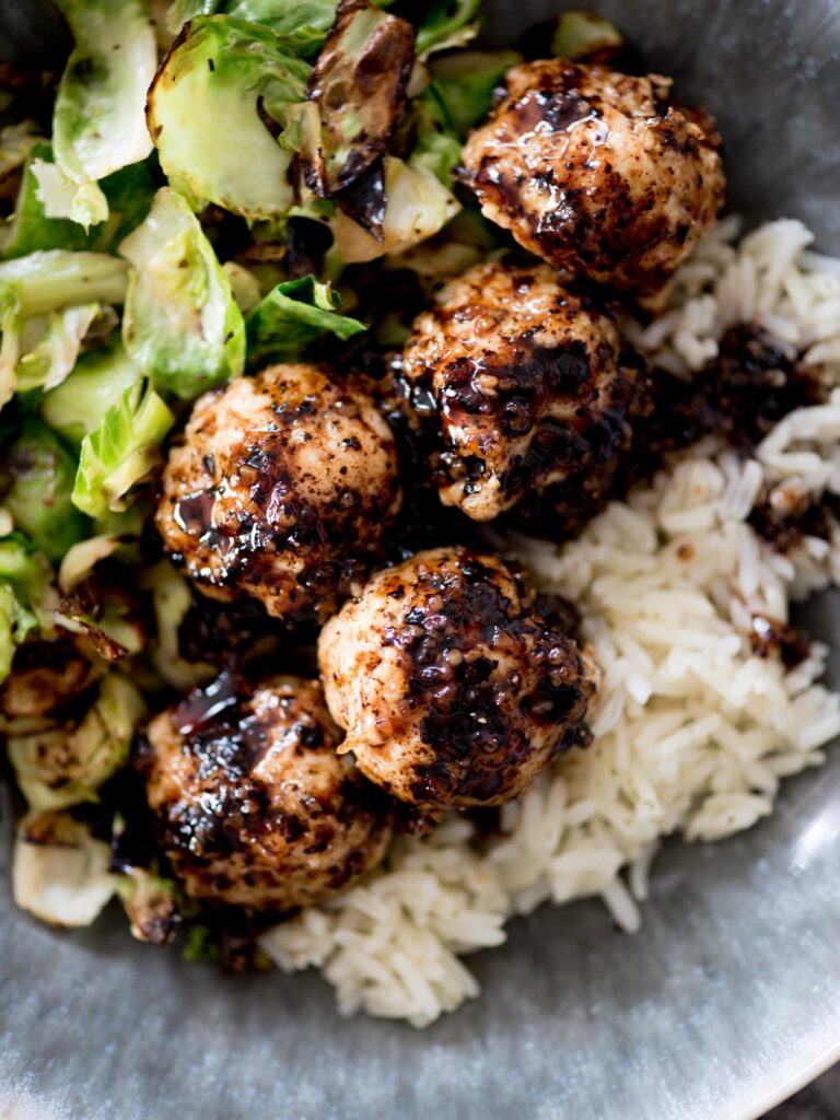 sticky sweet chicken meatballs in a bowl with rice and brussels sprouts