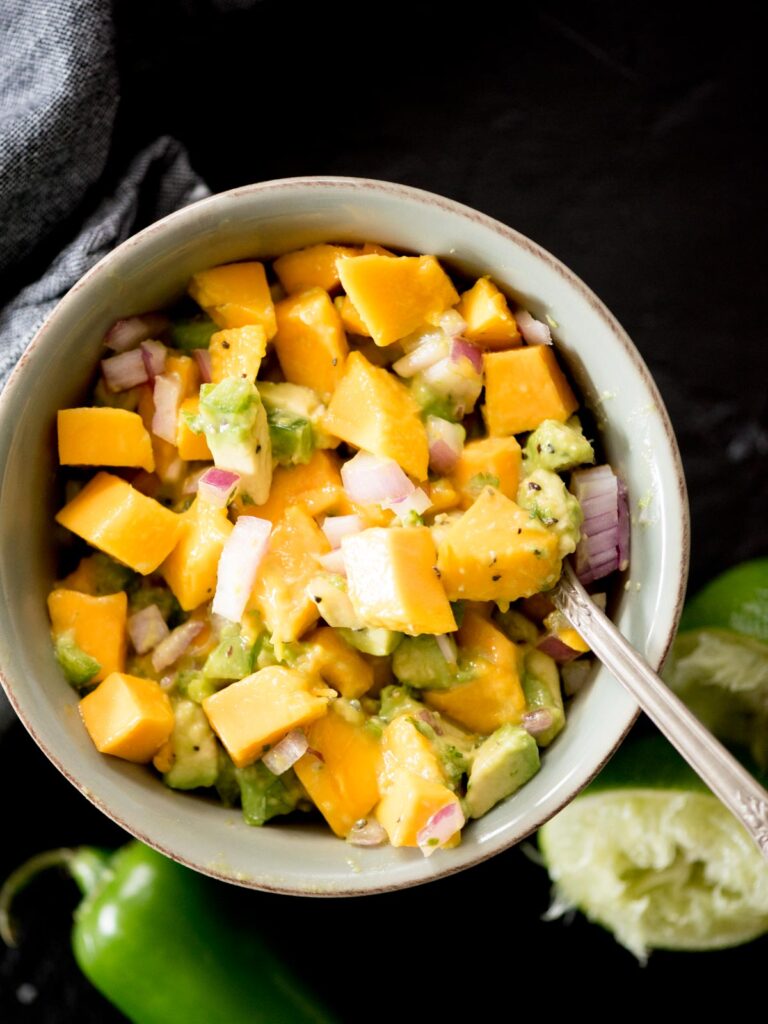 avocado mango salsa in a bowl being spooned out