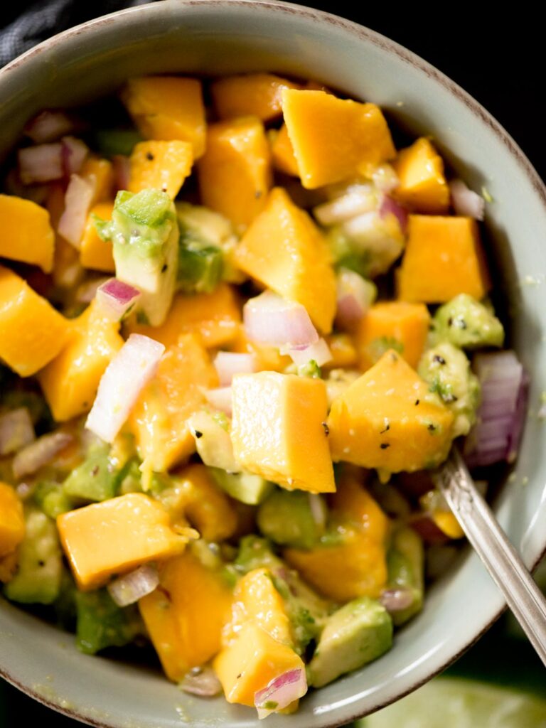 avocado mango salsa in a bowl being spooned out