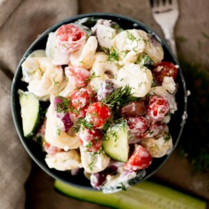 greek pasta salad in a bowl topped with fresh dill