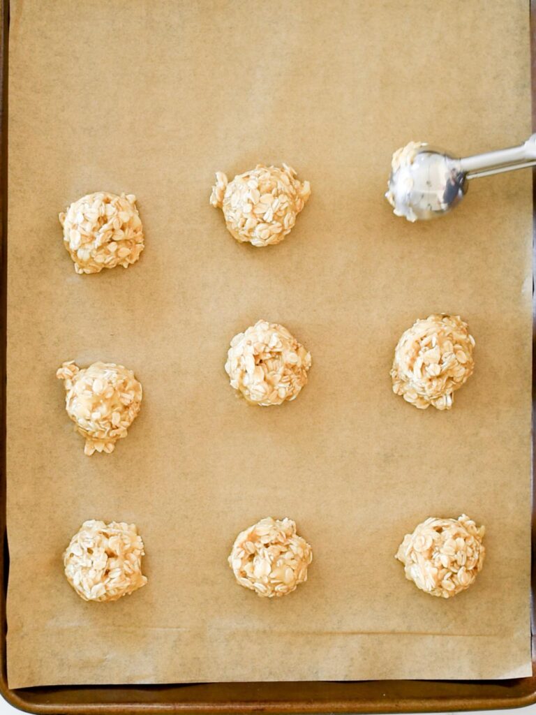 cookie dough being scooped on to a parchment lined baking sheet
