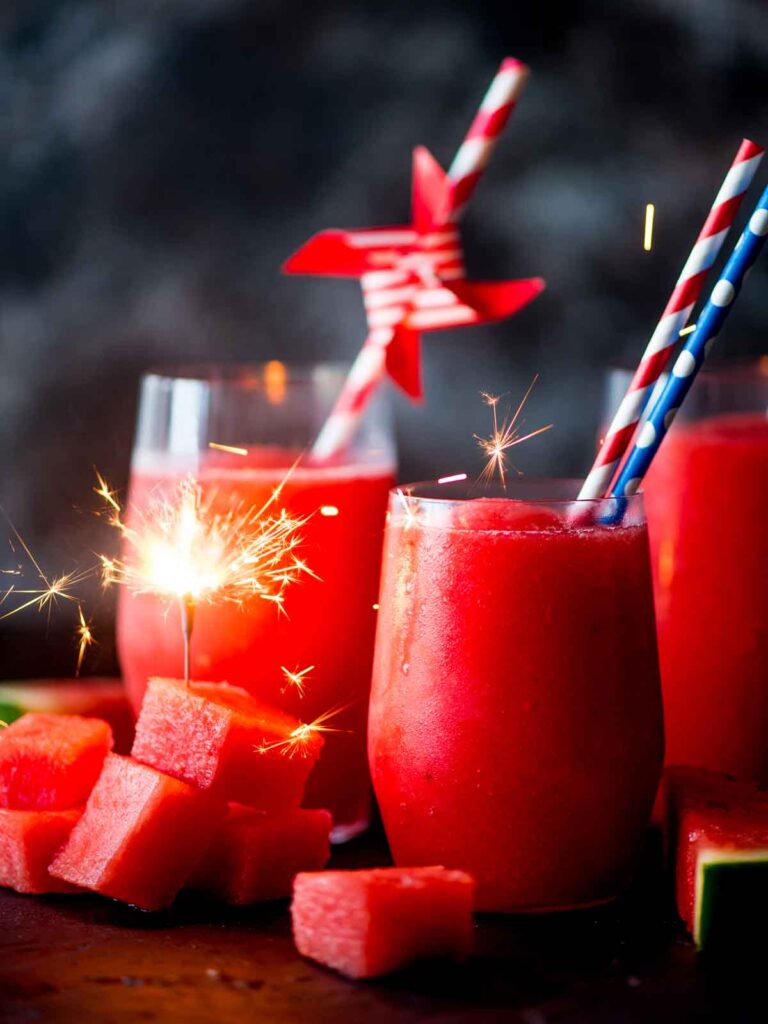 watermelon slush in glasses with paper straws and frozen watermelon chunks. Sparkler in watermelon