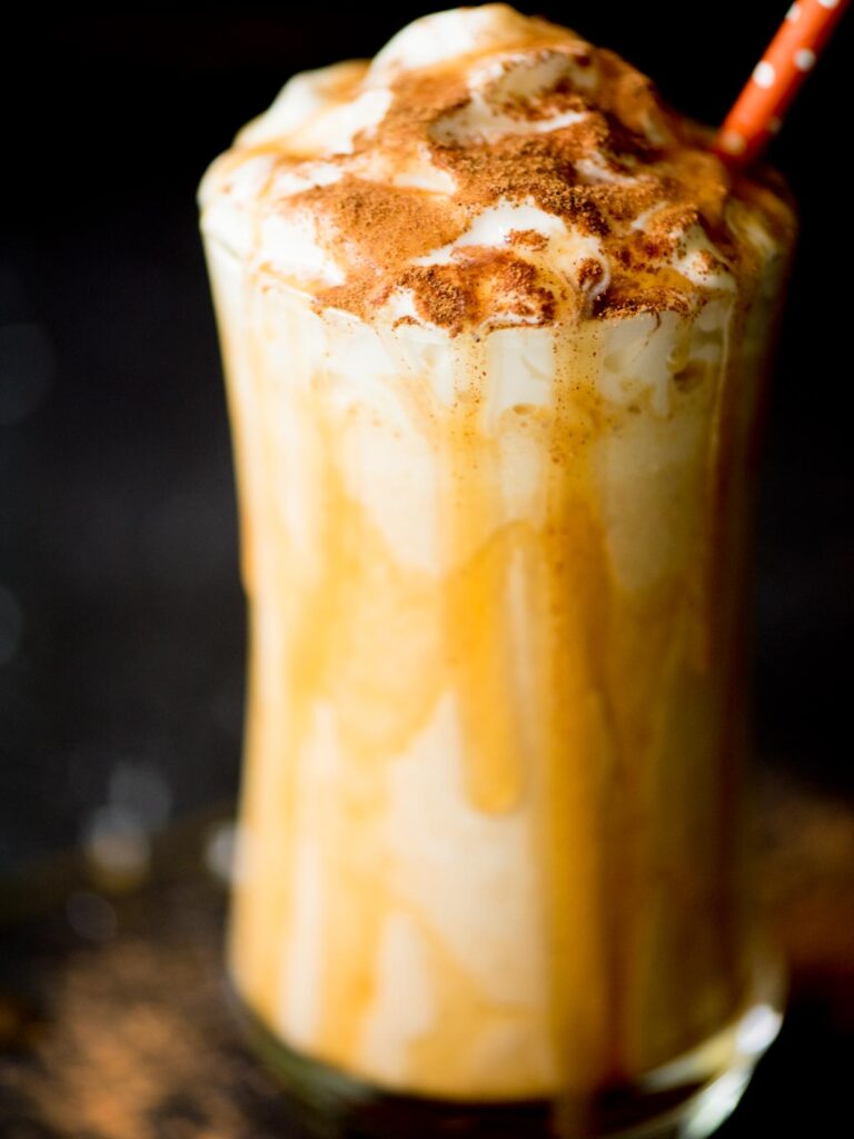 pumpkin milkshake in a glass with caramel drizzle