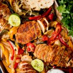 sheet pan chicken fajitas with creamy cilantro lime sauce, tortillas, and limes