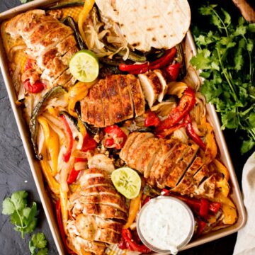 sheet pan chicken fajitas with creamy cilantro lime sauce, tortillas, and limes