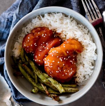 honey garlic chicken topped with sesame seeds over rice and green beans