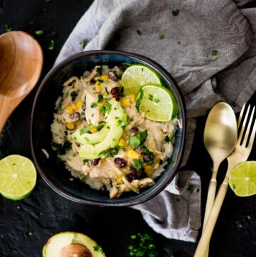 salsa verde chicken in a bowl over rice topped with avocado and lime