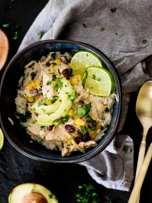 salsa verde chicken in a bowl over rice topped with avocado and lime