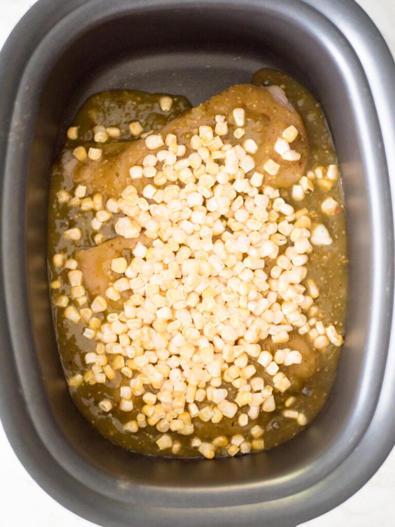 corn added to the crockpot with the chicken and salsa verde
