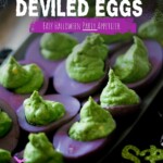 A platter of Halloween deviled eggs featuring purple-dyed whites and green filling.