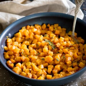 sauteed butternut squash in a skillet topped with fresh thyme