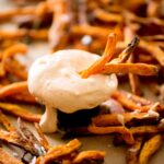 sweet potato fries dipping sauce with surrounded by sweet potatoes and some being dipped in it