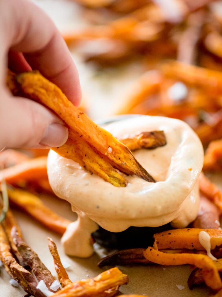 sweet potatoes being dipped into the fry sauce