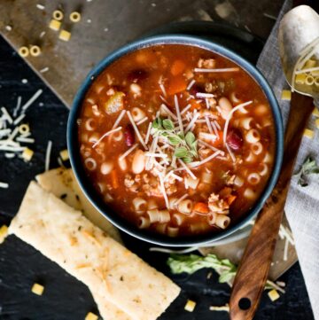 pasta e fagioli soup with breadsticks and topped with grated parmesan and oregano