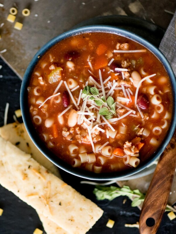 pasta e fagioli soup with breadsticks and topped with grated parmesan and oregano