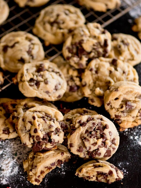 soft and chewy chocolate chip cookies on a cooling rack with flour scattered around