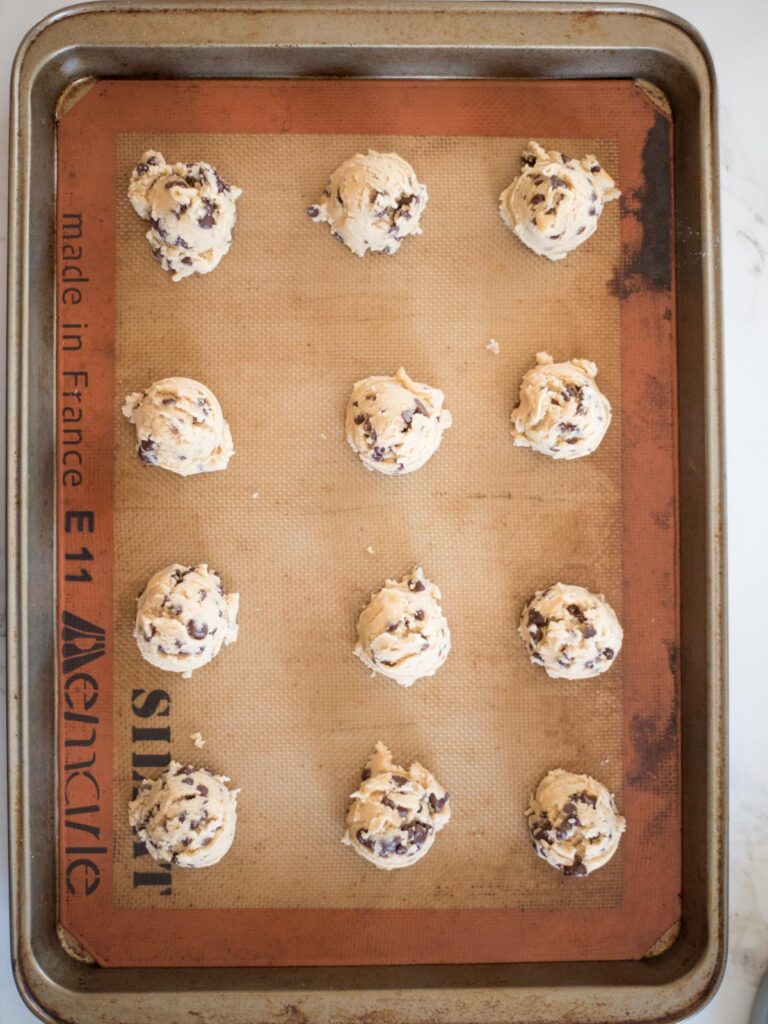 chewy chocolate chip cookie dough scooped on to a baking sheet