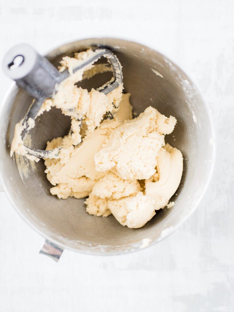 sugar cookie dough mixed together in a mixing bowl with the mixer attachment