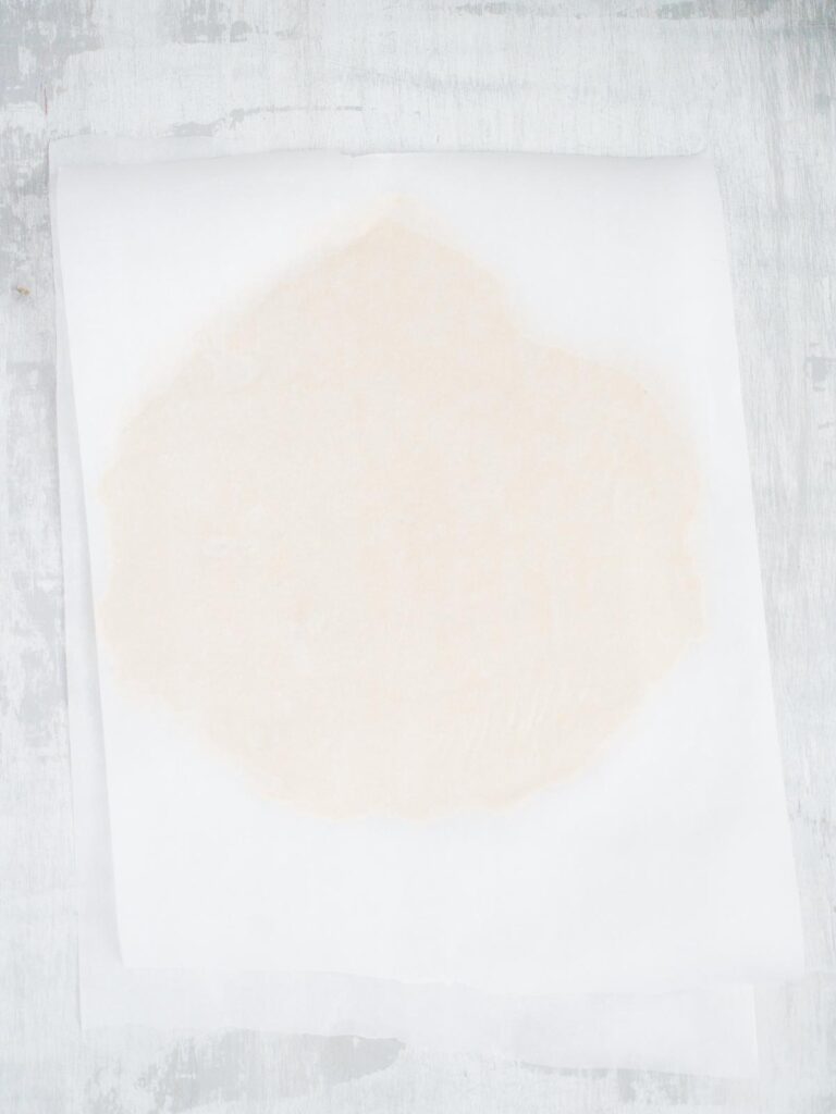 sugar cookie dough rolled out between two sheets of wax paper